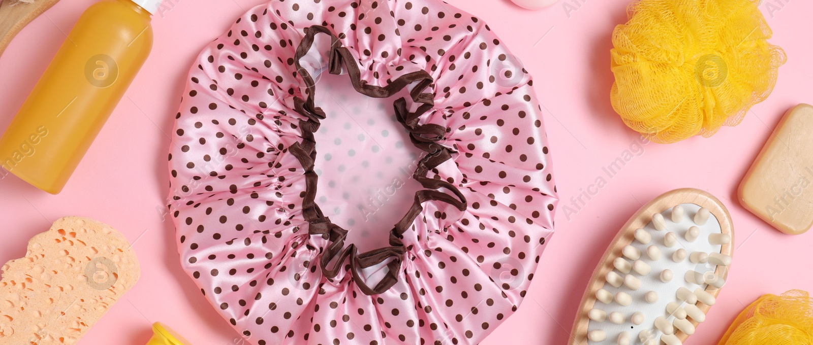 Photo of Shower cap and bath accessories on pink background, flat lay