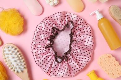 Photo of Shower cap and bath accessories on pink background, flat lay