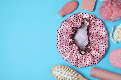 Photo of Shower cap and bath accessories on light blue background, flat lay. Space for text