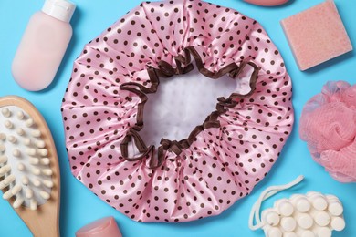 Photo of Shower cap and bath accessories on light blue background, flat lay