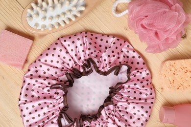 Photo of Shower cap and bath accessories on wooden background, flat lay