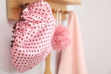 Photo of Shower cap, mesh sponge and towel on rack indoors, closeup. Space for text