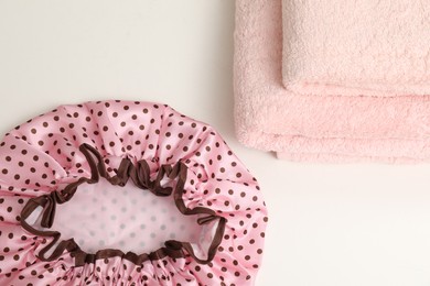 Photo of Shower cap and towels on white table, top view