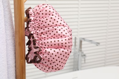 Photo of Shower cap and towel on rack in bathroom, closeup. Space for text