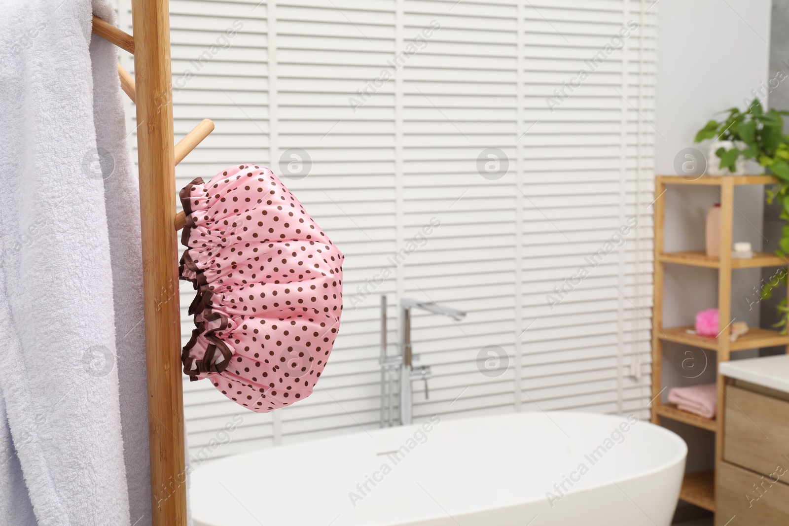 Photo of Shower cap and towel on rack in bathroom, space for text