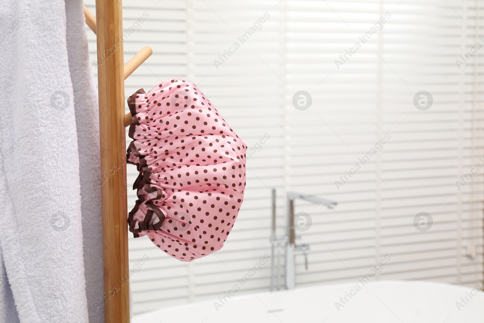 Photo of Shower cap and towel on rack in bathroom, space for text