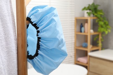 Photo of Shower cap and towel on rack in bathroom, closeup