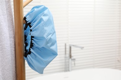 Photo of Shower cap and towel on rack in bathroom, space for text