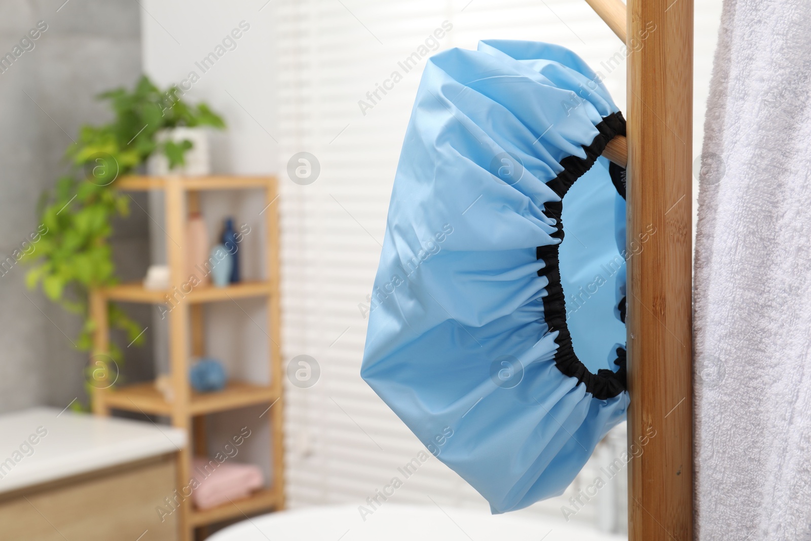 Photo of Shower cap and towel on rack in bathroom, closeup