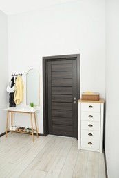 Photo of Mirror, rack with clothes, chest of drawers and shoe storage bench in hallway. Interior design