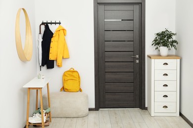 Photo of Mirror, rack with clothes, chest of drawers and shoe storage bench in hallway. Interior design