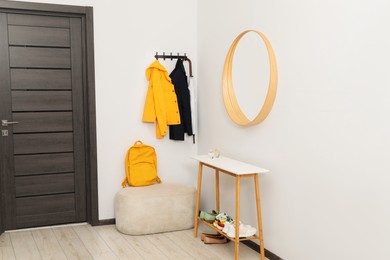 Photo of Mirror, rack with clothes and shoe storage bench in hallway. Interior design