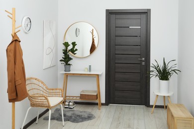 Photo of Clothing rack, mirror, houseplant and stylish furniture in hallway