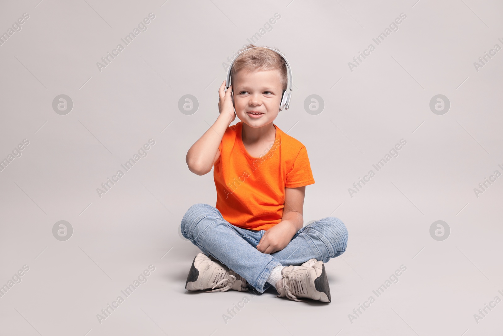 Photo of Little boy listening to music on light grey background