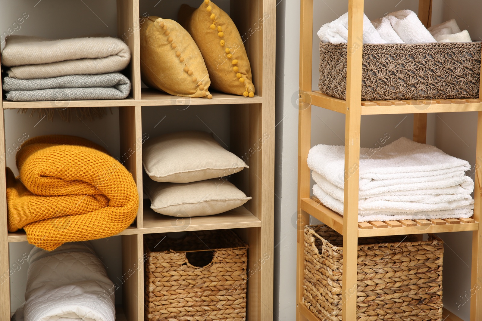 Photo of Home textile organization. Folded towels, blankets and pillows on shelving units indoors, closeup