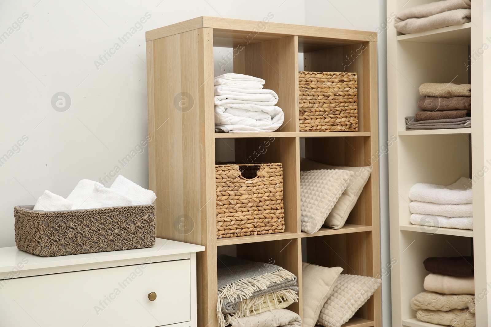 Photo of Home textile organization. Folded towels, blankets and pillows on shelving units indoors