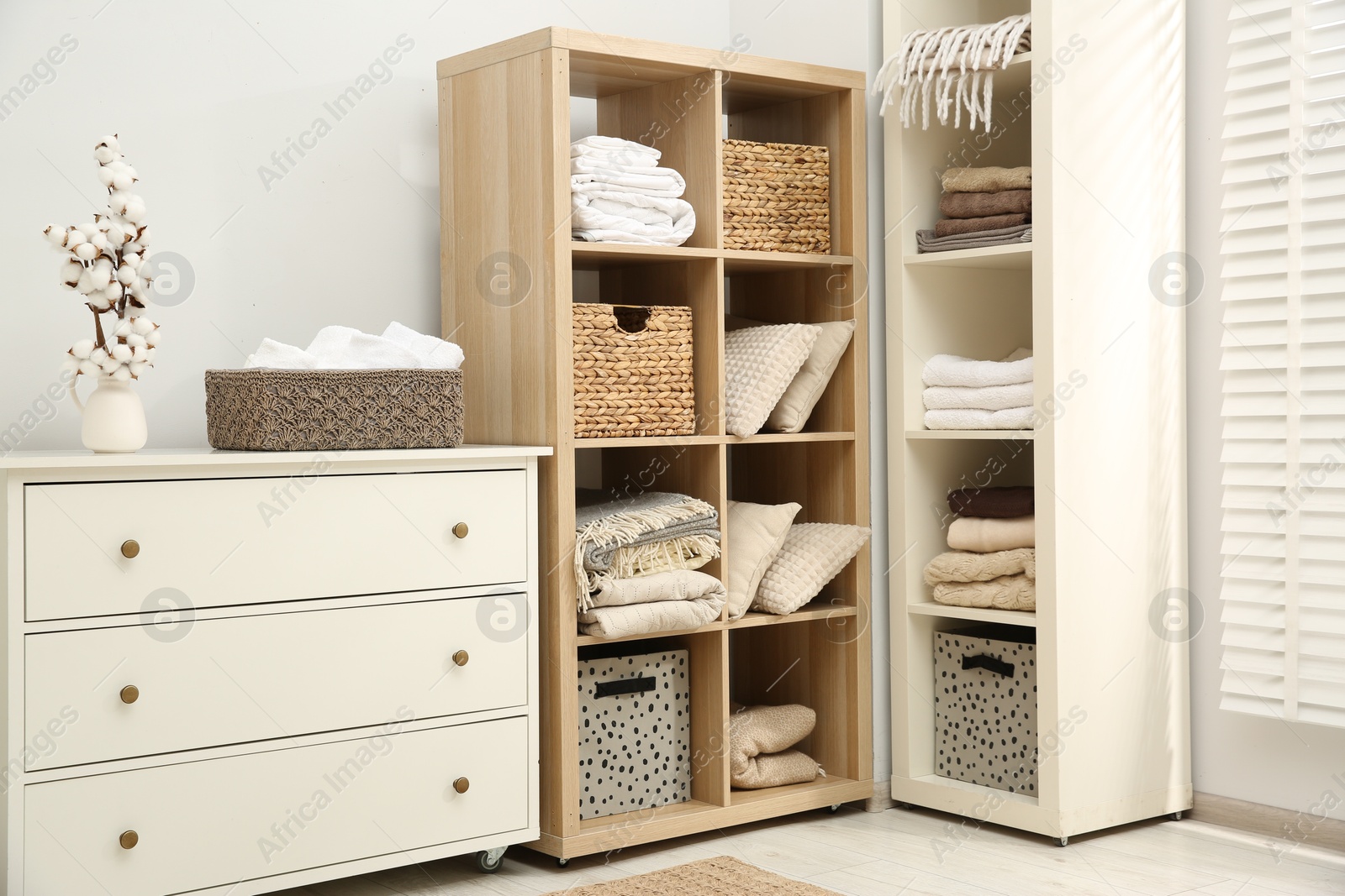 Photo of Home textile organization. Folded towels, blankets and pillows on shelving units indoors