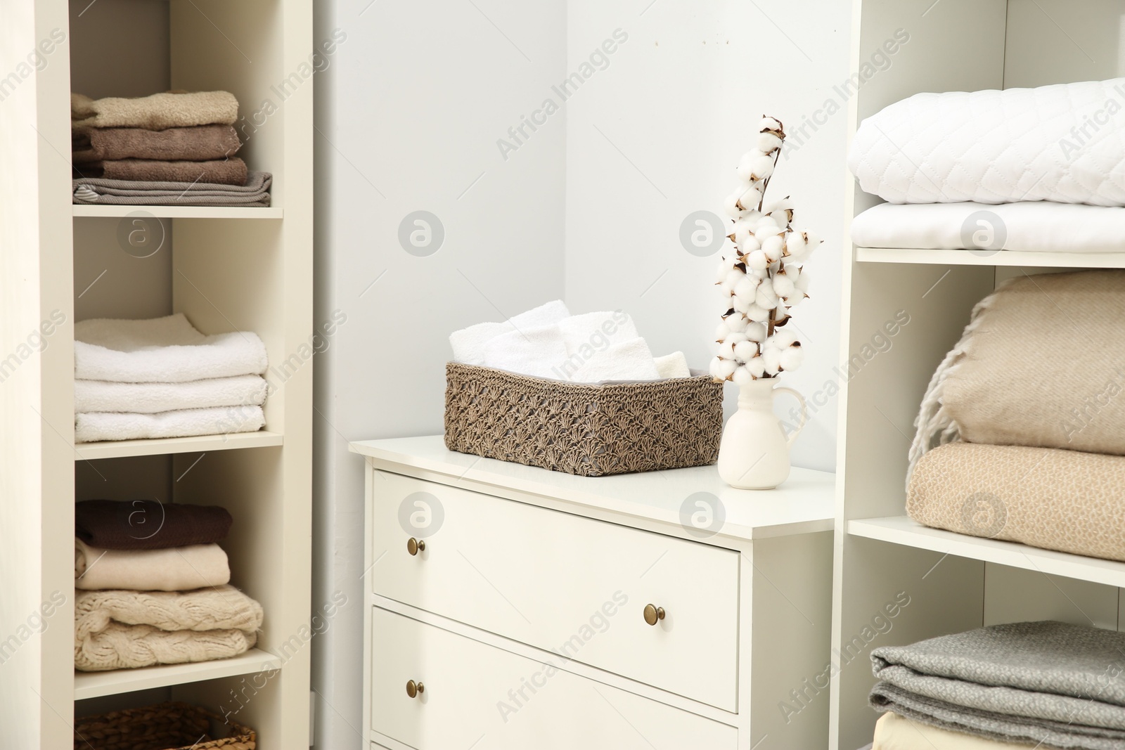 Photo of Home textile organization. Folded towels and blankets on shelving units indoors