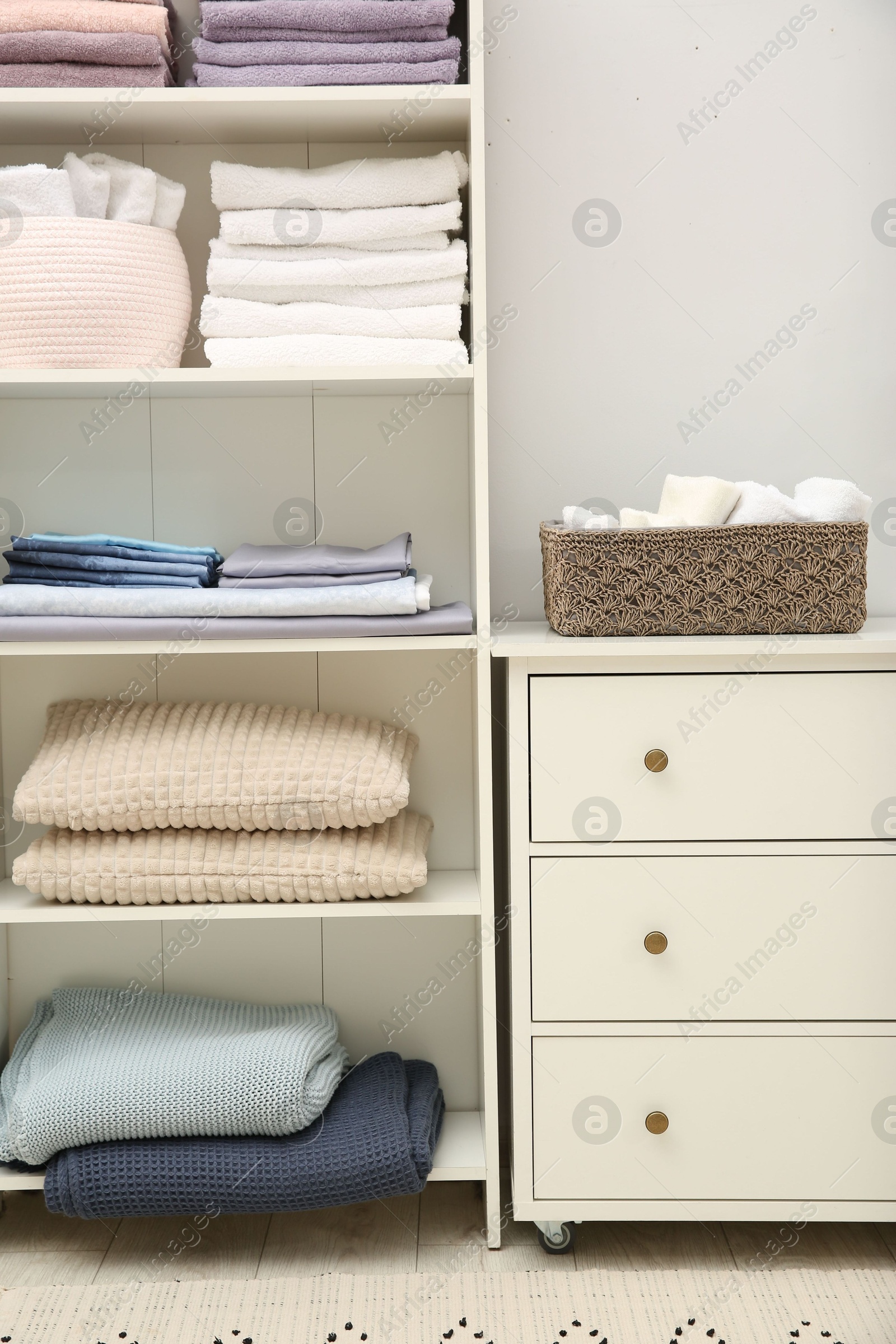 Photo of Home textile organization. Folded towels, bedsheets and pillows on shelving unit indoors