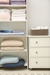 Photo of Home textile organization. Folded towels, bedsheets and pillows on shelving unit indoors