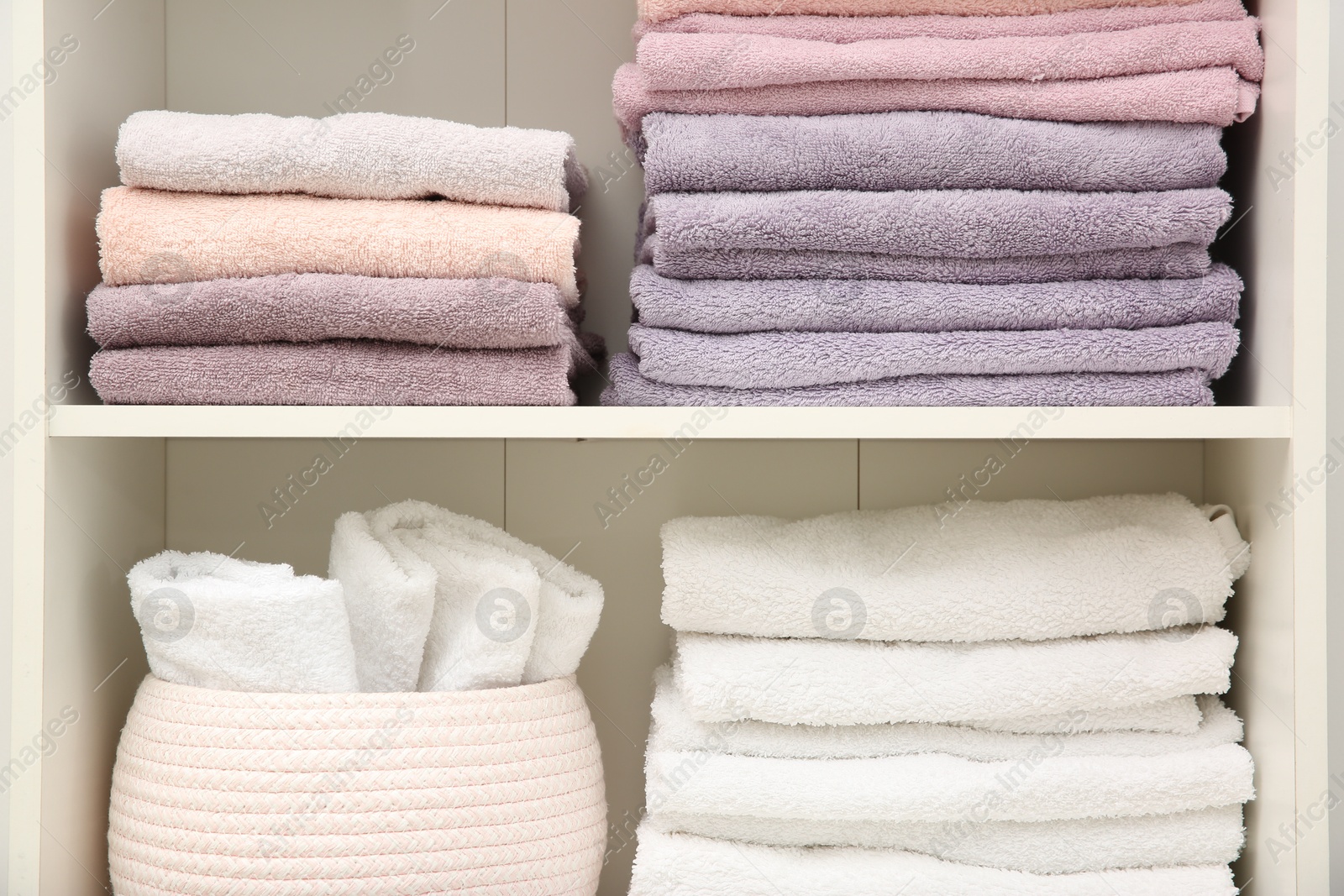 Photo of Home textile organization. Folded towels on shelving unit indoors, closeup