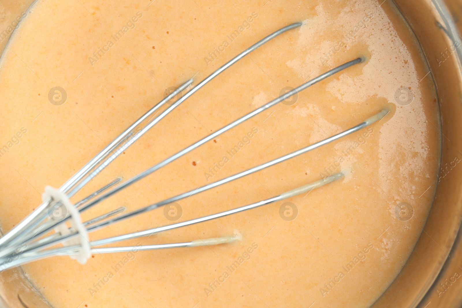 Photo of Bowl with dough for pumpkin pancakes and whisk, closeup