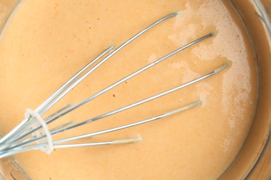 Photo of Bowl with dough for pumpkin pancakes and whisk, closeup