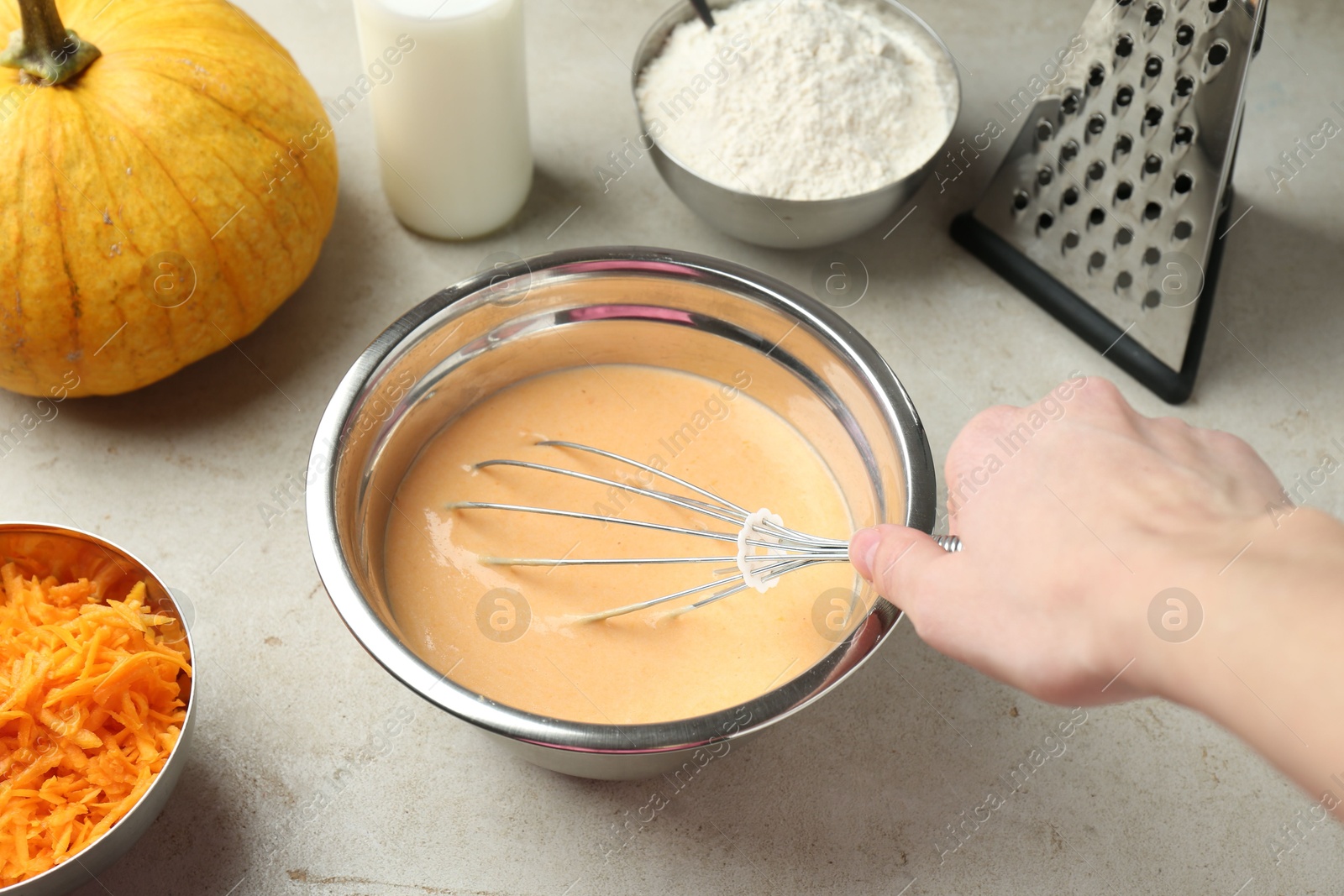 Photo of Making pumpkin pancakes. Woman mixing dough at light table, closeup