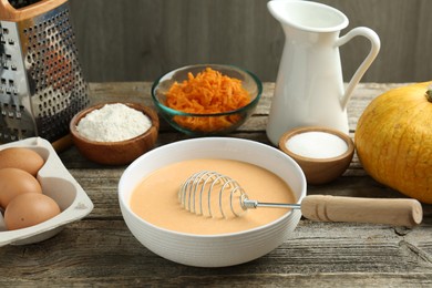 Photo of Bowl with dough and ingredients for pumpkin pancakes on wooden table