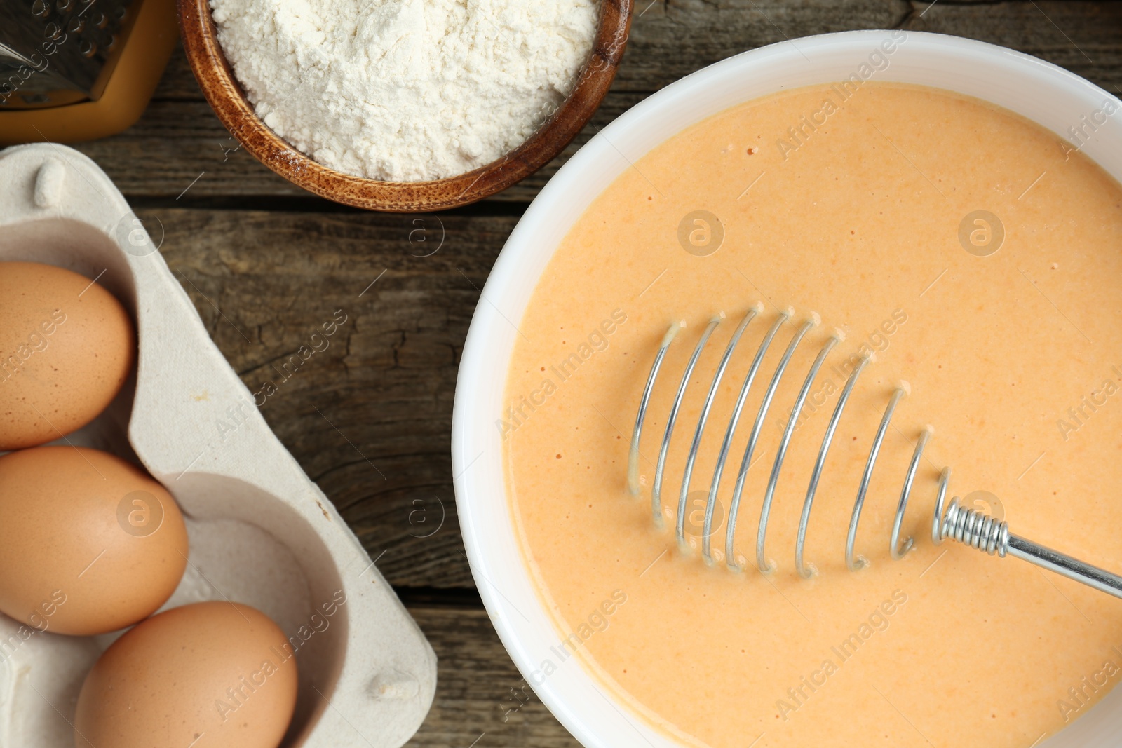 Photo of Bowl with dough and ingredients for pumpkin pancakes on wooden table, closeup