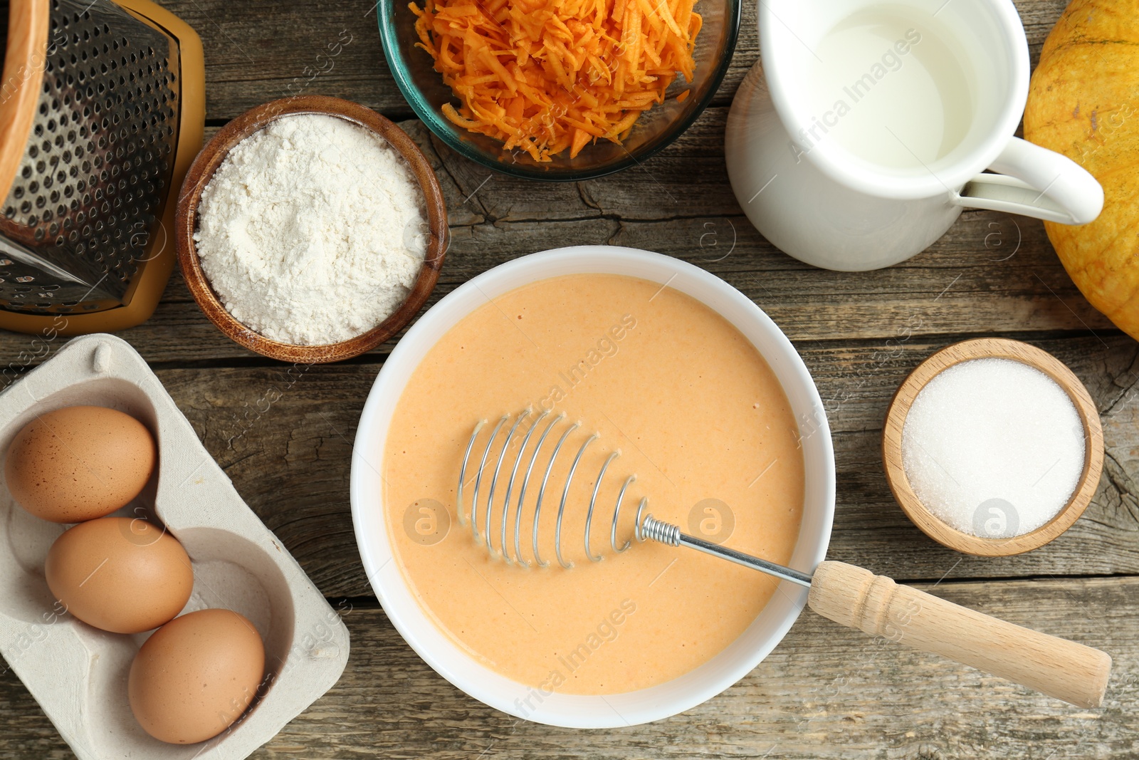 Photo of Bowl with dough and ingredients for pumpkin pancakes on wooden table, flat lay