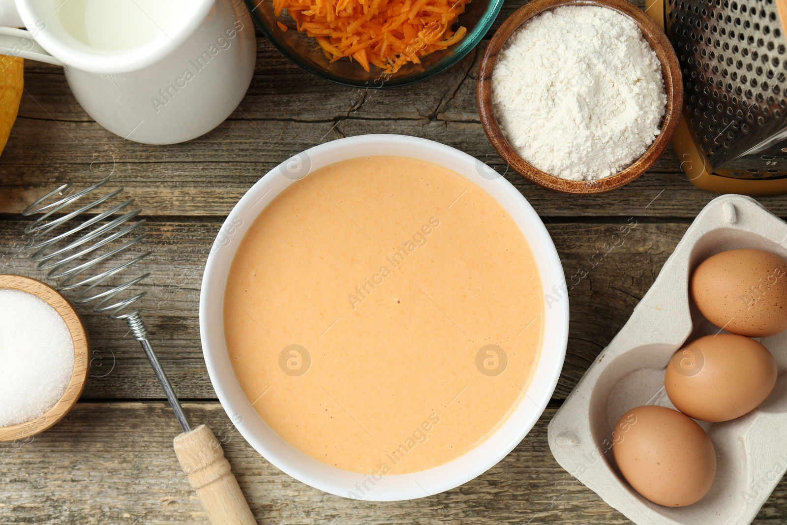 Photo of Bowl with dough and ingredients for pumpkin pancakes on wooden table, flat lay