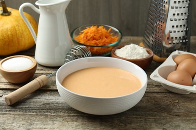 Photo of Bowl with dough and ingredients for pumpkin pancakes on wooden table