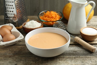 Photo of Bowl with dough and ingredients for pumpkin pancakes on wooden table