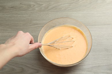 Photo of Making pumpkin pancakes. Woman mixing dough at wooden table, closeup