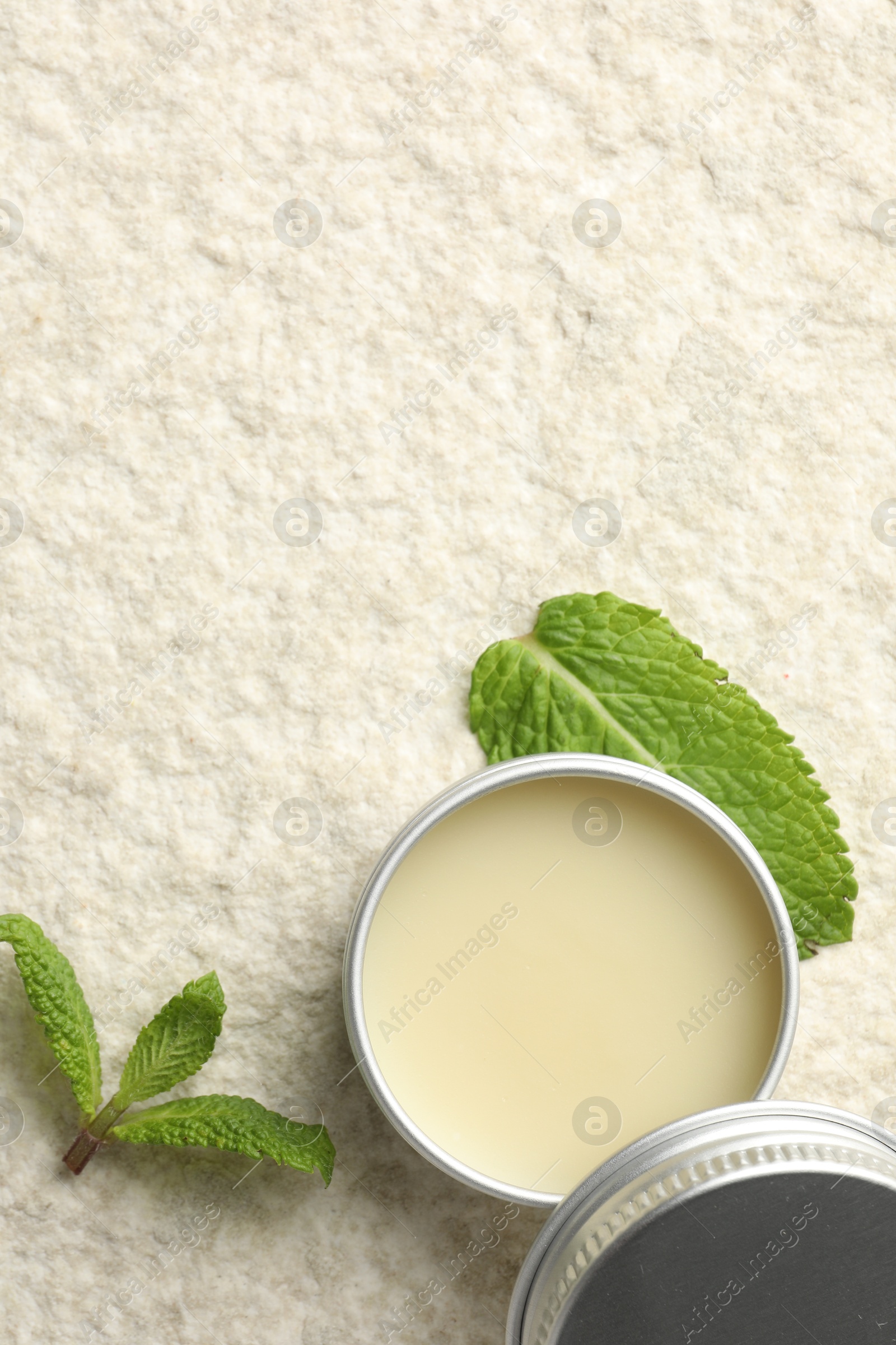 Photo of Mint lip balm and green leaves on beige textured background, top view. Space for text