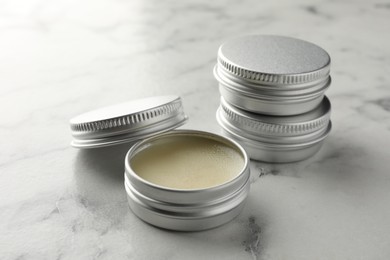 Photo of Lip balms on white marble table, closeup. Cosmetic product