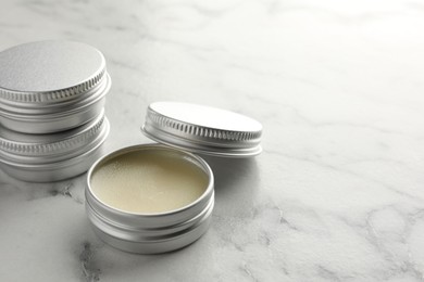 Photo of Lip balms on white marble table, closeup. Space for text