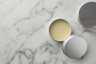 Photo of Lip balms on white marble background, top view. Space for text