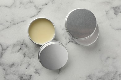 Photo of Lip balms on white marble background, top view. Cosmetic product