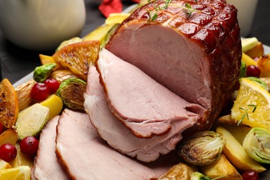 Photo of Tasty baked ham served with vegetables and oranges on table, closeup