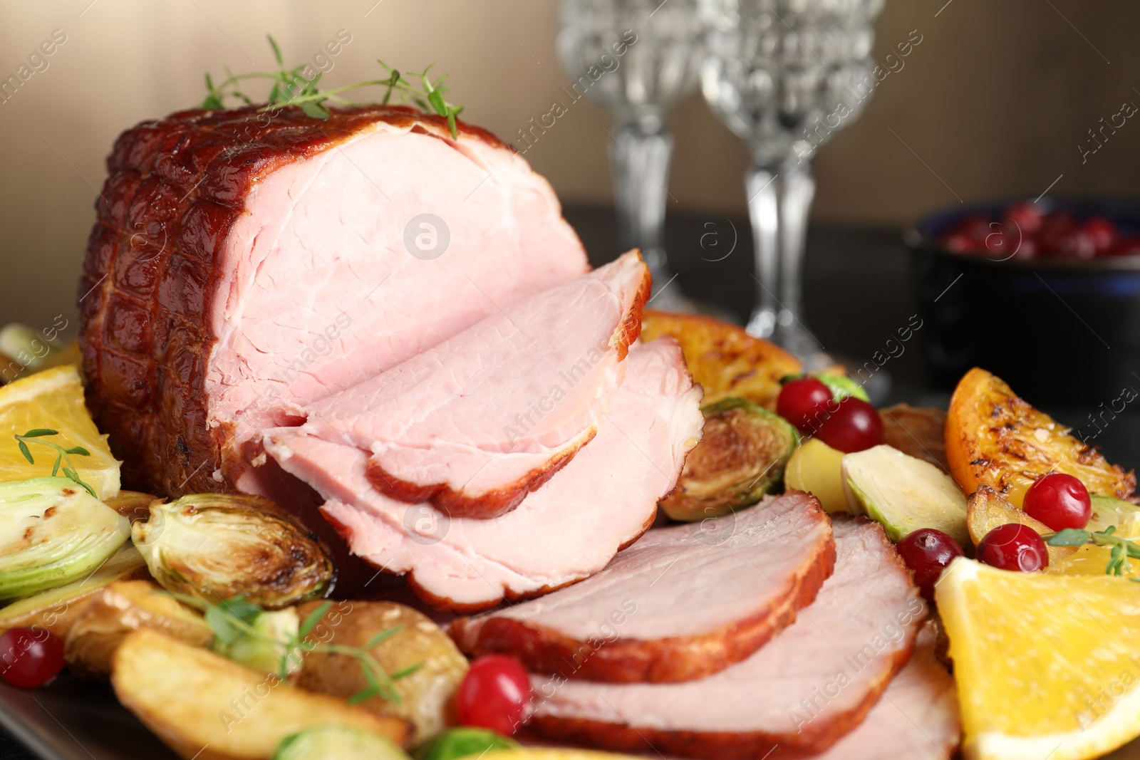 Photo of Tasty baked ham served with vegetables and oranges on table, closeup