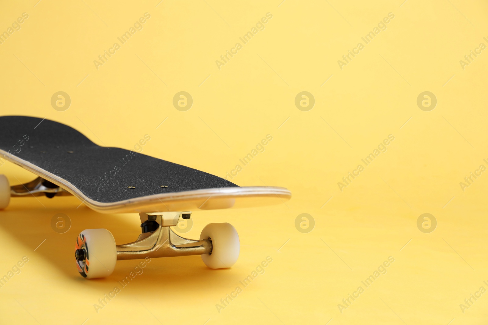 Photo of One skateboard on yellow background, closeup. Space for text