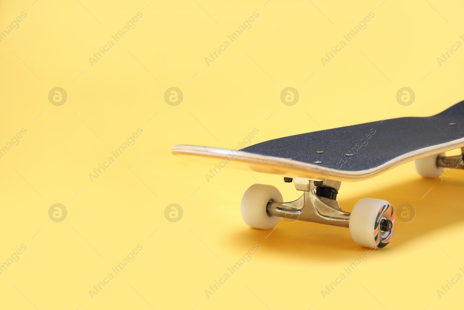 Photo of One skateboard on yellow background, closeup. Space for text