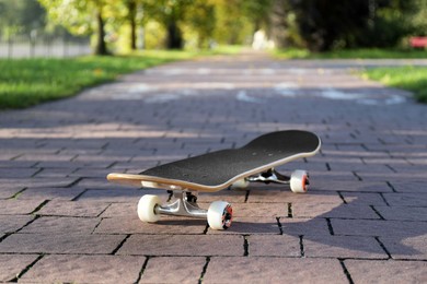 Photo of One modern skateboard on paved pathway outdoors, closeup