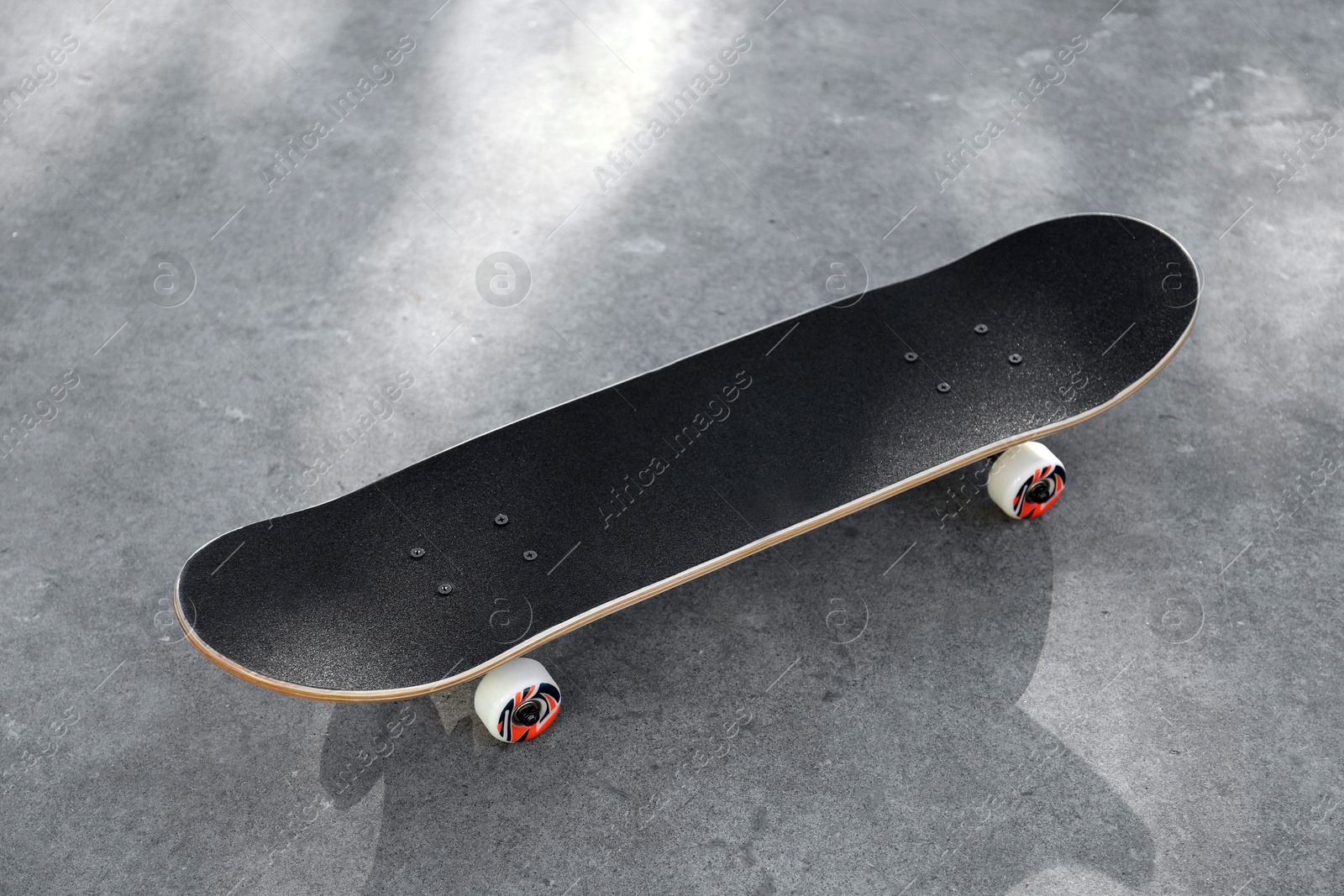 Photo of One modern skateboard with black griptape on ground outdoors