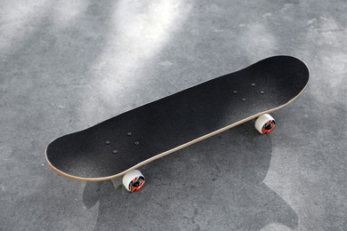 Photo of One modern skateboard with black griptape on ground outdoors