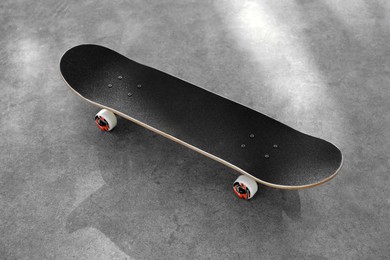 Photo of One modern skateboard with black griptape on ground outdoors