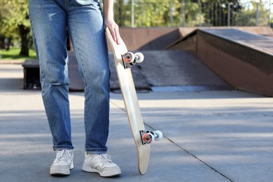 Photo of Woman with modern skateboard in skatepark, closeup. Space for text