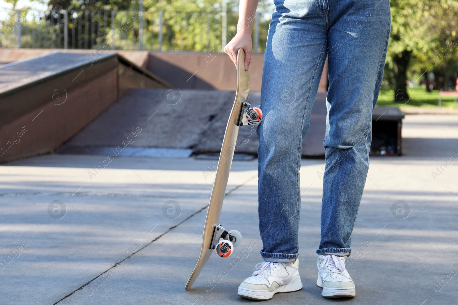 Photo of Woman with modern skateboard in skatepark, closeup. Space for text